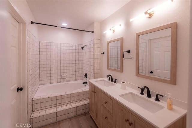 bathroom featuring vanity, tiled shower / bath combo, and wood-type flooring