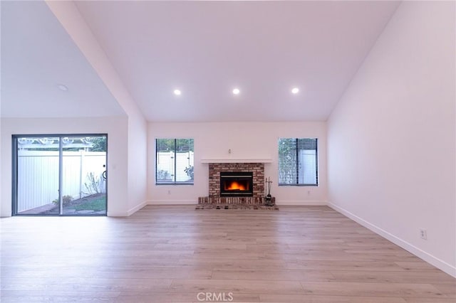 unfurnished living room featuring high vaulted ceiling, light wood-type flooring, and a fireplace