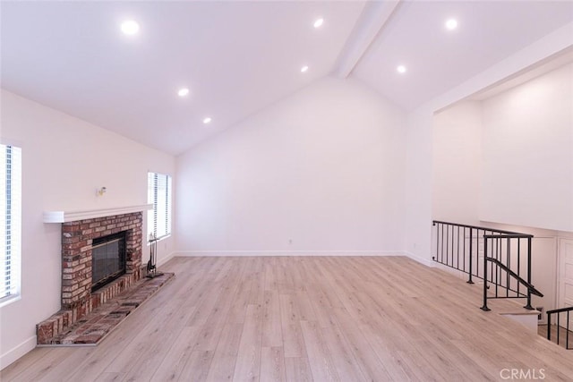 unfurnished living room featuring beamed ceiling, a fireplace, high vaulted ceiling, and light wood-type flooring