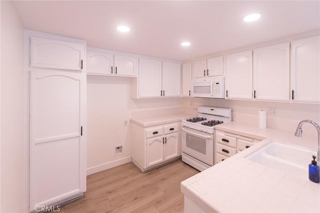 kitchen featuring sink, white cabinets, white appliances, and light hardwood / wood-style flooring