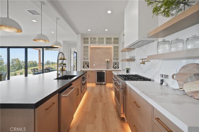 kitchen featuring stainless steel appliances, a kitchen island with sink, wine cooler, hanging light fixtures, and sink