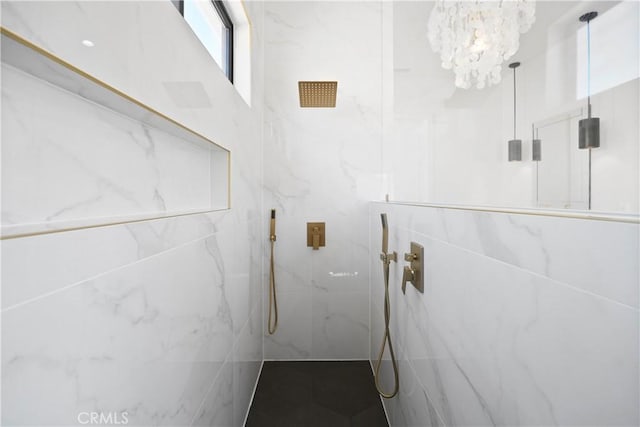 bathroom featuring tiled shower and an inviting chandelier