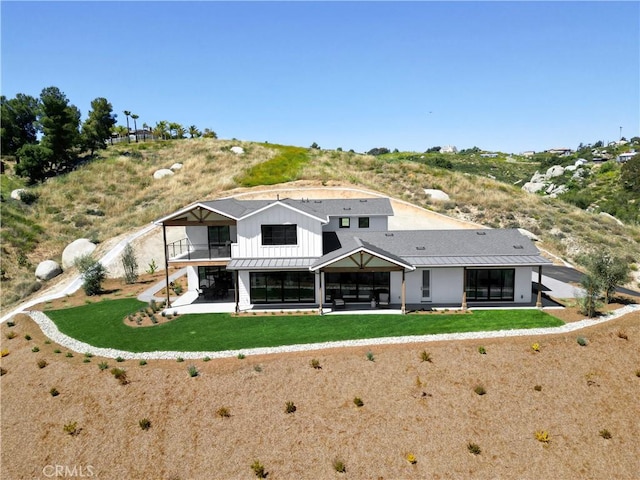 rear view of property with a lawn, a balcony, and a patio