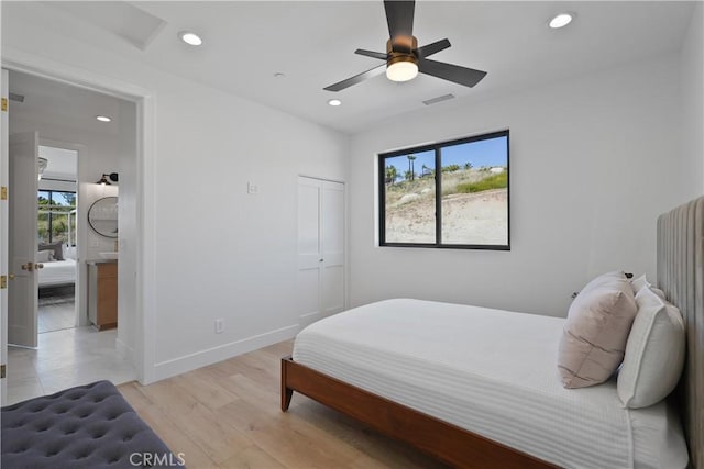 bedroom with ceiling fan, ensuite bathroom, light hardwood / wood-style flooring, and a closet