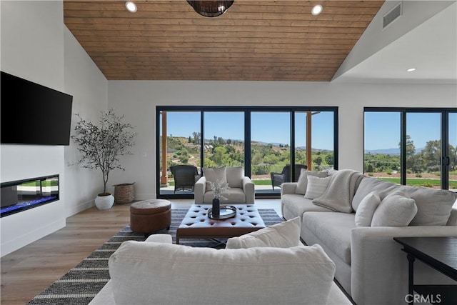 living room with lofted ceiling, a healthy amount of sunlight, wood ceiling, and light hardwood / wood-style floors