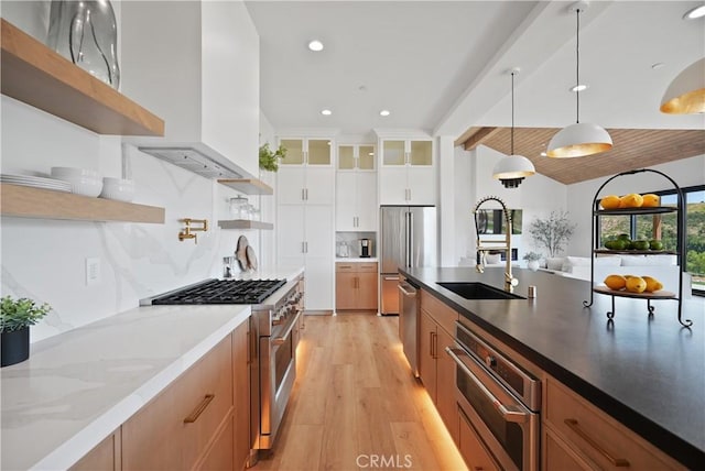 kitchen with backsplash, pendant lighting, high end appliances, light hardwood / wood-style flooring, and white cabinets