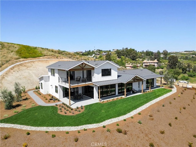 back of house featuring a balcony, a lawn, and a patio