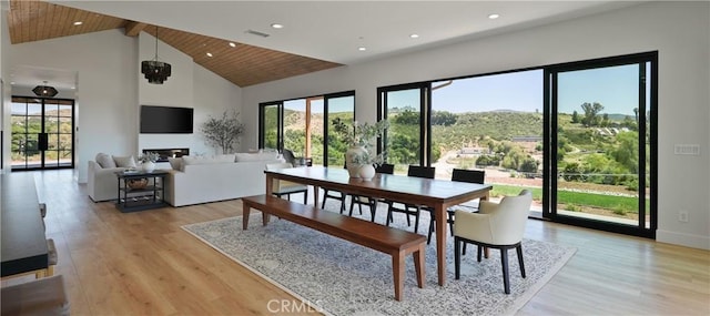 dining area featuring a notable chandelier, light hardwood / wood-style floors, beamed ceiling, wood ceiling, and high vaulted ceiling