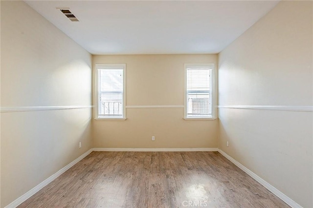 spare room with a wealth of natural light and hardwood / wood-style flooring