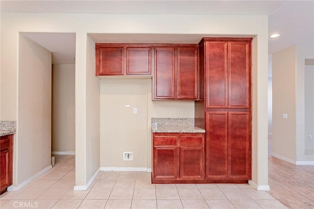 kitchen featuring light tile patterned flooring and light stone counters