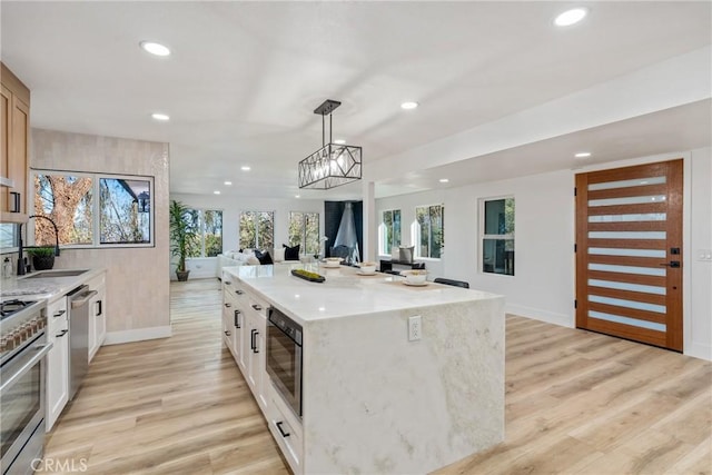 kitchen with stainless steel appliances, a kitchen island, pendant lighting, white cabinets, and sink