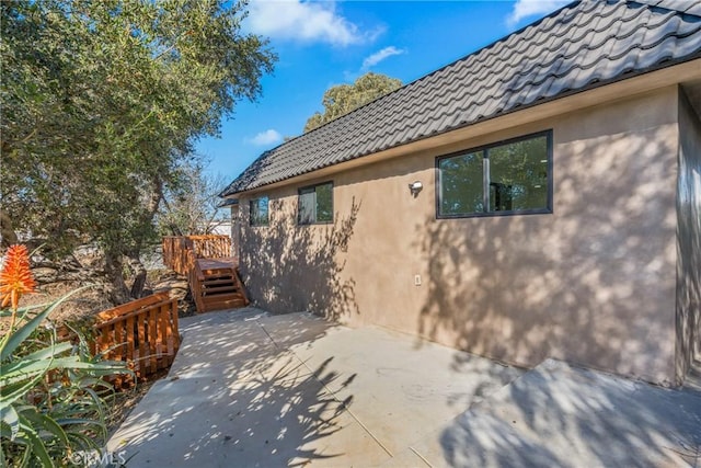 view of side of home with a wooden deck and a patio