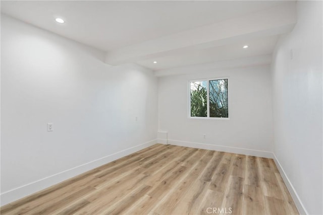 unfurnished room featuring light hardwood / wood-style floors and beamed ceiling