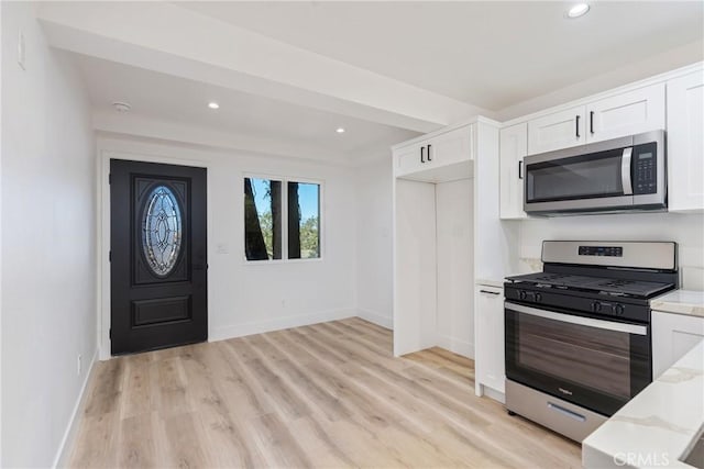 kitchen featuring appliances with stainless steel finishes, light hardwood / wood-style flooring, white cabinets, and light stone countertops