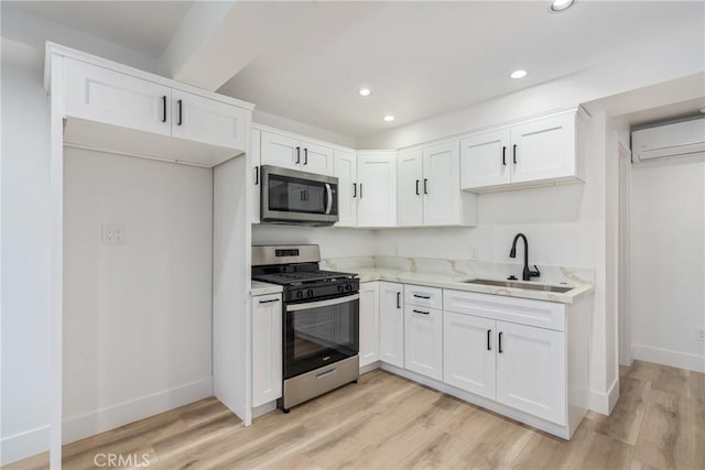 kitchen featuring a wall mounted air conditioner, appliances with stainless steel finishes, white cabinetry, and sink