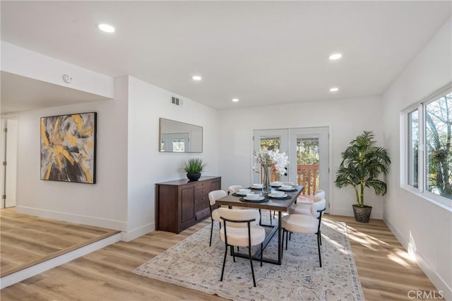 dining room featuring a healthy amount of sunlight, french doors, and light hardwood / wood-style floors