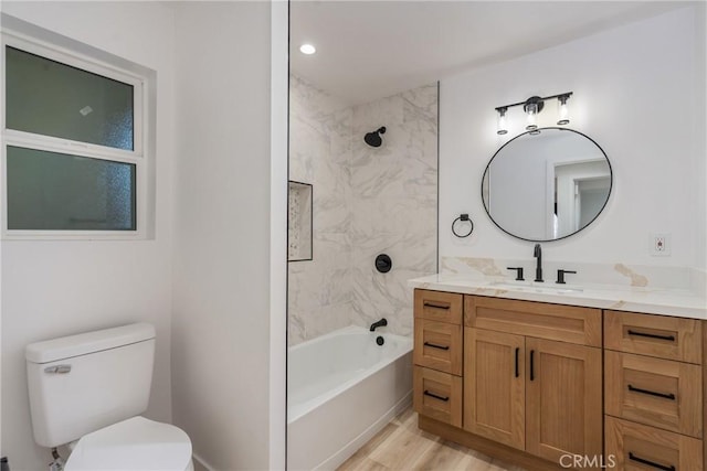 full bathroom with toilet, tiled shower / bath, wood-type flooring, and vanity