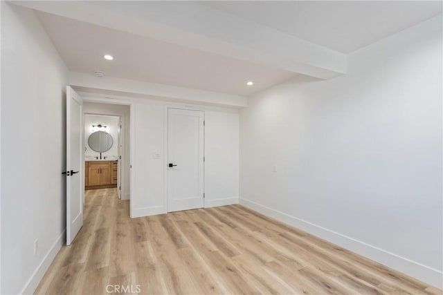 unfurnished bedroom featuring a closet, beamed ceiling, and light hardwood / wood-style flooring