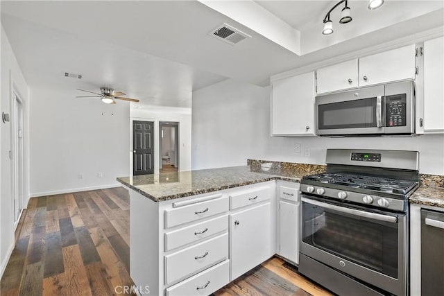 kitchen with kitchen peninsula, appliances with stainless steel finishes, and white cabinets