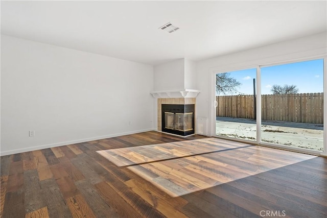 unfurnished living room featuring hardwood / wood-style floors and a tiled fireplace