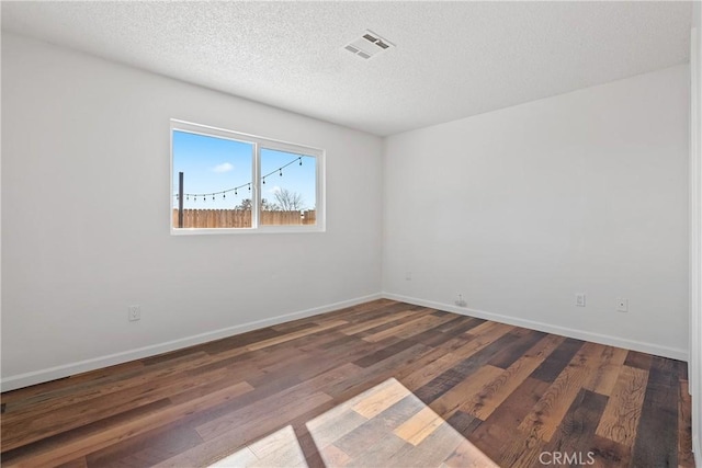 unfurnished room with a textured ceiling and dark hardwood / wood-style floors