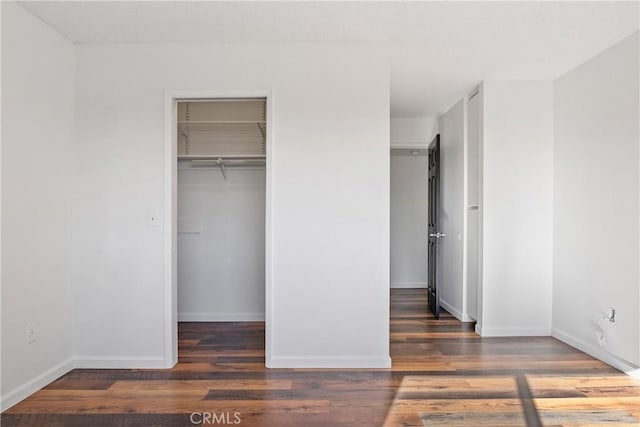 unfurnished bedroom featuring a closet, dark hardwood / wood-style flooring, and a walk in closet