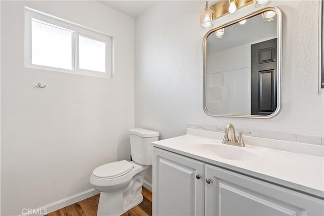 bathroom with toilet, hardwood / wood-style flooring, and vanity