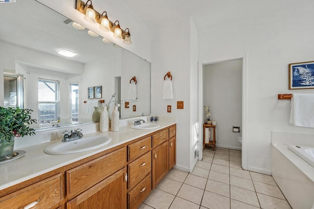 bathroom featuring toilet, vanity, tile patterned floors, and tiled tub