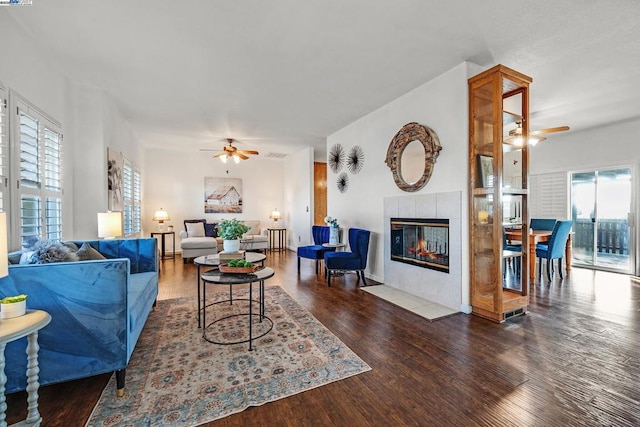 living room featuring ceiling fan, a fireplace, and dark hardwood / wood-style floors