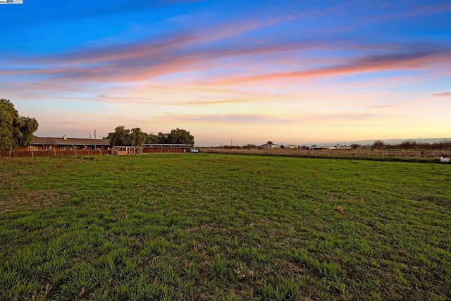 yard at dusk featuring a rural view