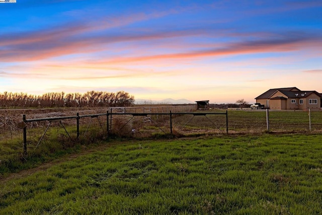 yard at dusk featuring a rural view