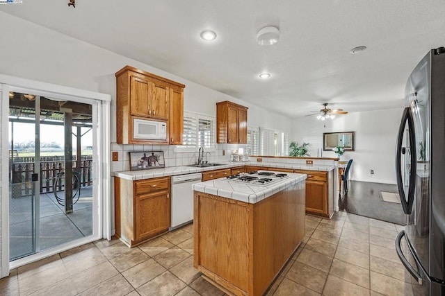 kitchen featuring white appliances, a kitchen island, sink, tile countertops, and ceiling fan