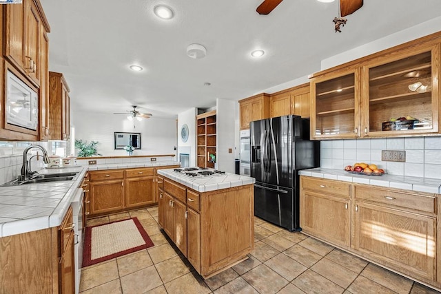 kitchen featuring tile counters, sink, white appliances, and a center island