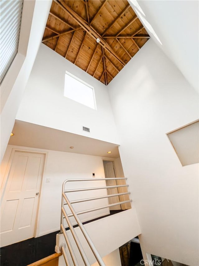 stairs with wooden ceiling and high vaulted ceiling