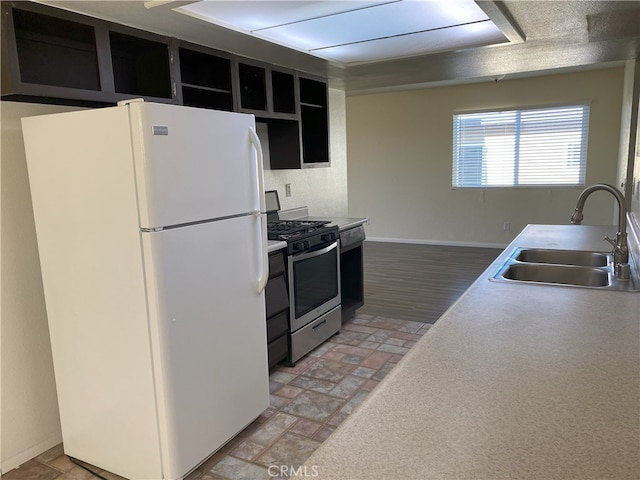 kitchen with stainless steel gas range oven, sink, and white fridge