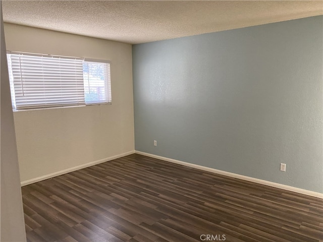 empty room featuring dark wood-type flooring and a textured ceiling