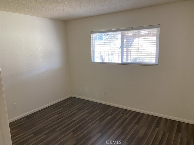 unfurnished room with dark hardwood / wood-style flooring, a wealth of natural light, and a textured ceiling