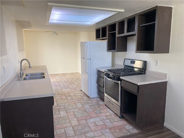 kitchen featuring white refrigerator, stainless steel gas stove, sink, ceiling fan, and dark brown cabinets