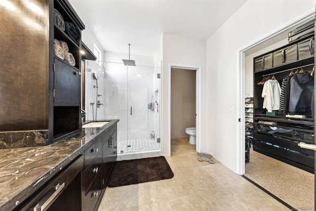 bathroom with vanity, toilet, and a shower with door