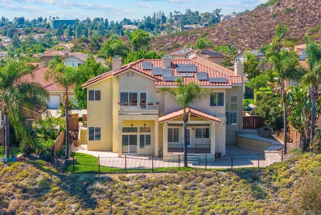 rear view of property featuring solar panels and a patio