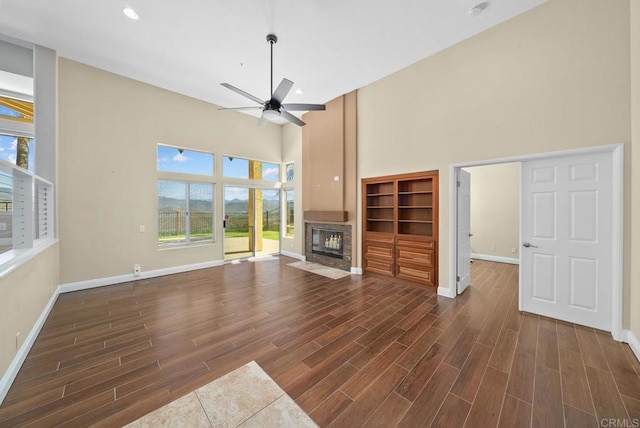 unfurnished living room featuring ceiling fan and a towering ceiling