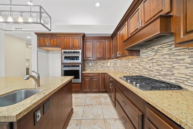 kitchen featuring custom exhaust hood, stainless steel appliances, decorative backsplash, light stone counters, and sink