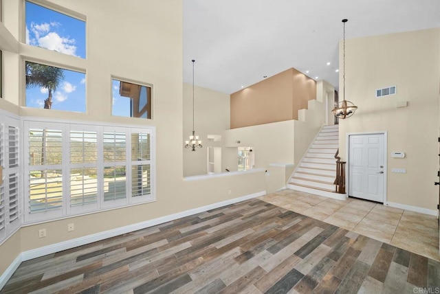 unfurnished living room featuring a towering ceiling and an inviting chandelier