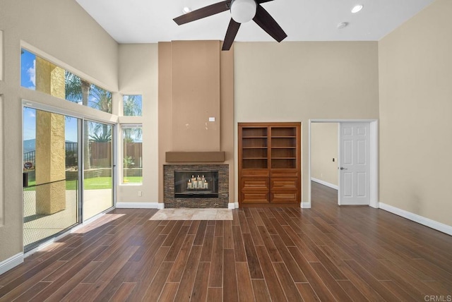 unfurnished living room featuring ceiling fan, a fireplace, and a towering ceiling