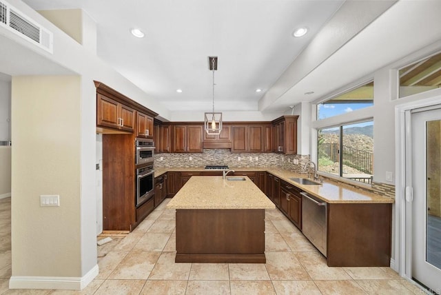 kitchen with dishwasher, sink, hanging light fixtures, a kitchen island with sink, and light stone counters