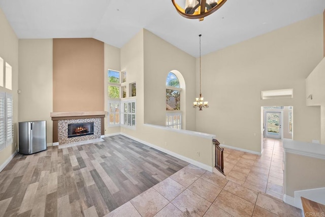 unfurnished living room featuring high vaulted ceiling, light tile patterned floors, and an inviting chandelier