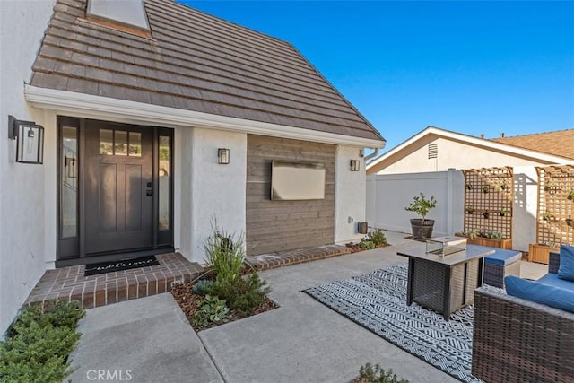 exterior space with outdoor lounge area, fence, and stucco siding