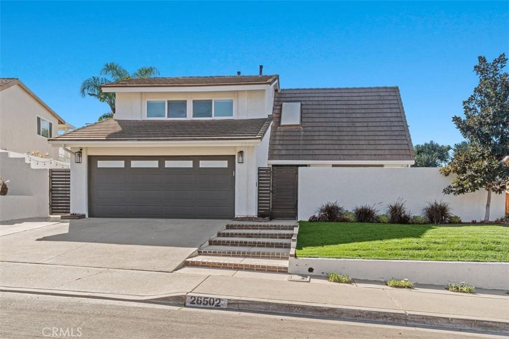 view of front of house featuring driveway, a tiled roof, a front lawn, and stucco siding