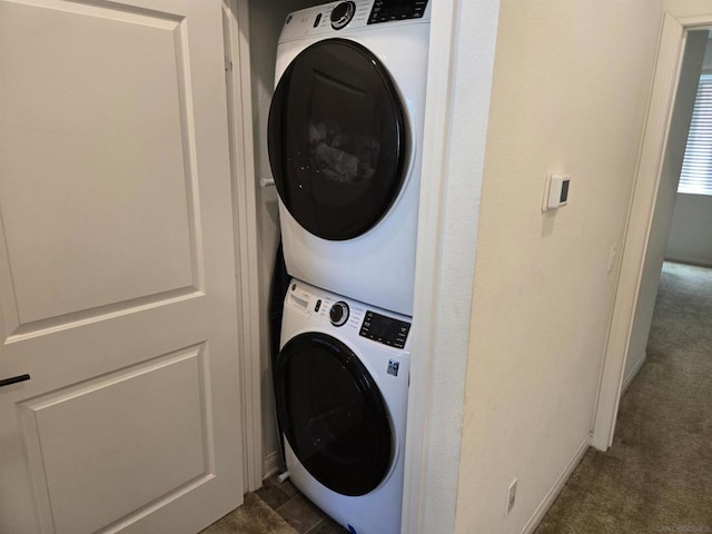 laundry area with stacked washer / drying machine and dark colored carpet