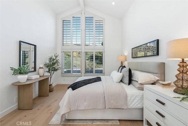 bedroom with high vaulted ceiling and light hardwood / wood-style flooring